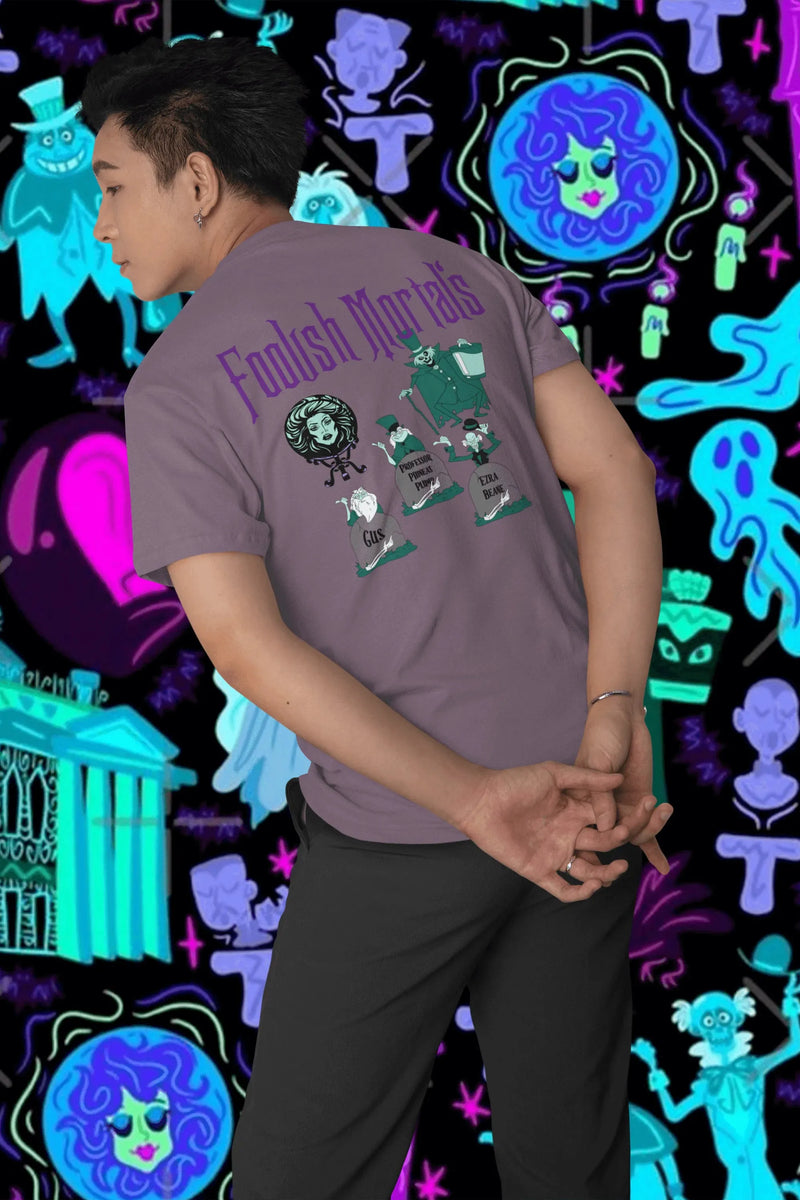 Man wearing purple Haunted Mansion T-shirt with 'Foolish Mortals' and ghost characters
