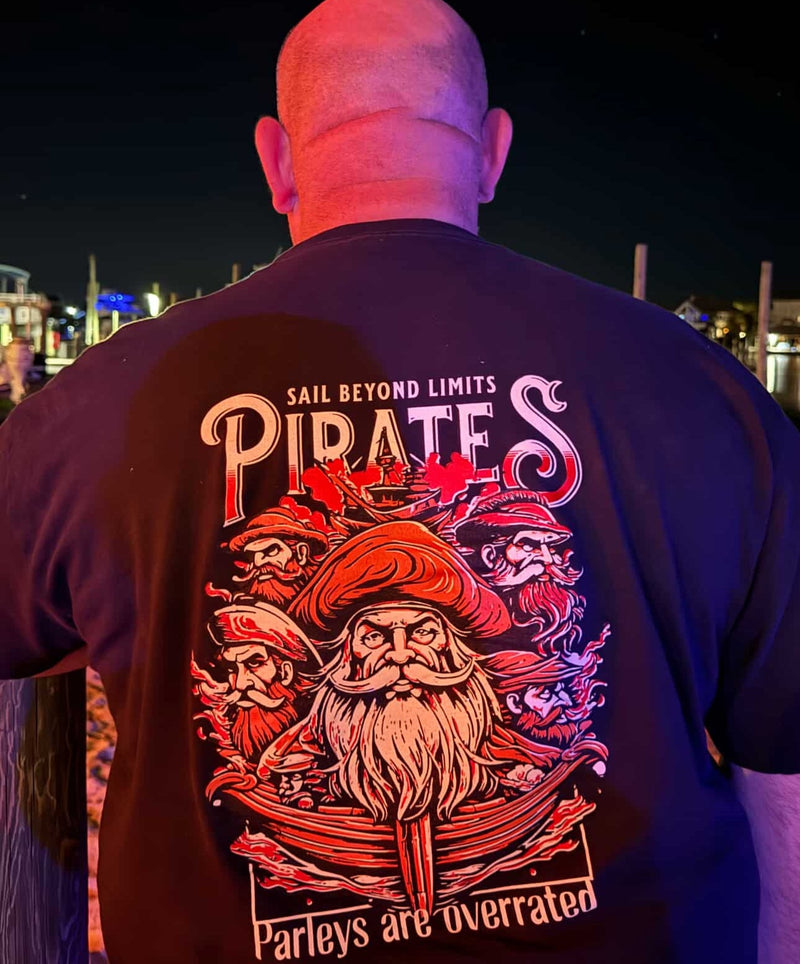 Man wearing pirate graphic t-shirt at night, featuring "Sail Beyond Limits Pirates" text.