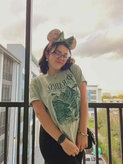 Woman wearing Disney-inspired mouse ears and a Paradise Falls t-shirt on a balcony