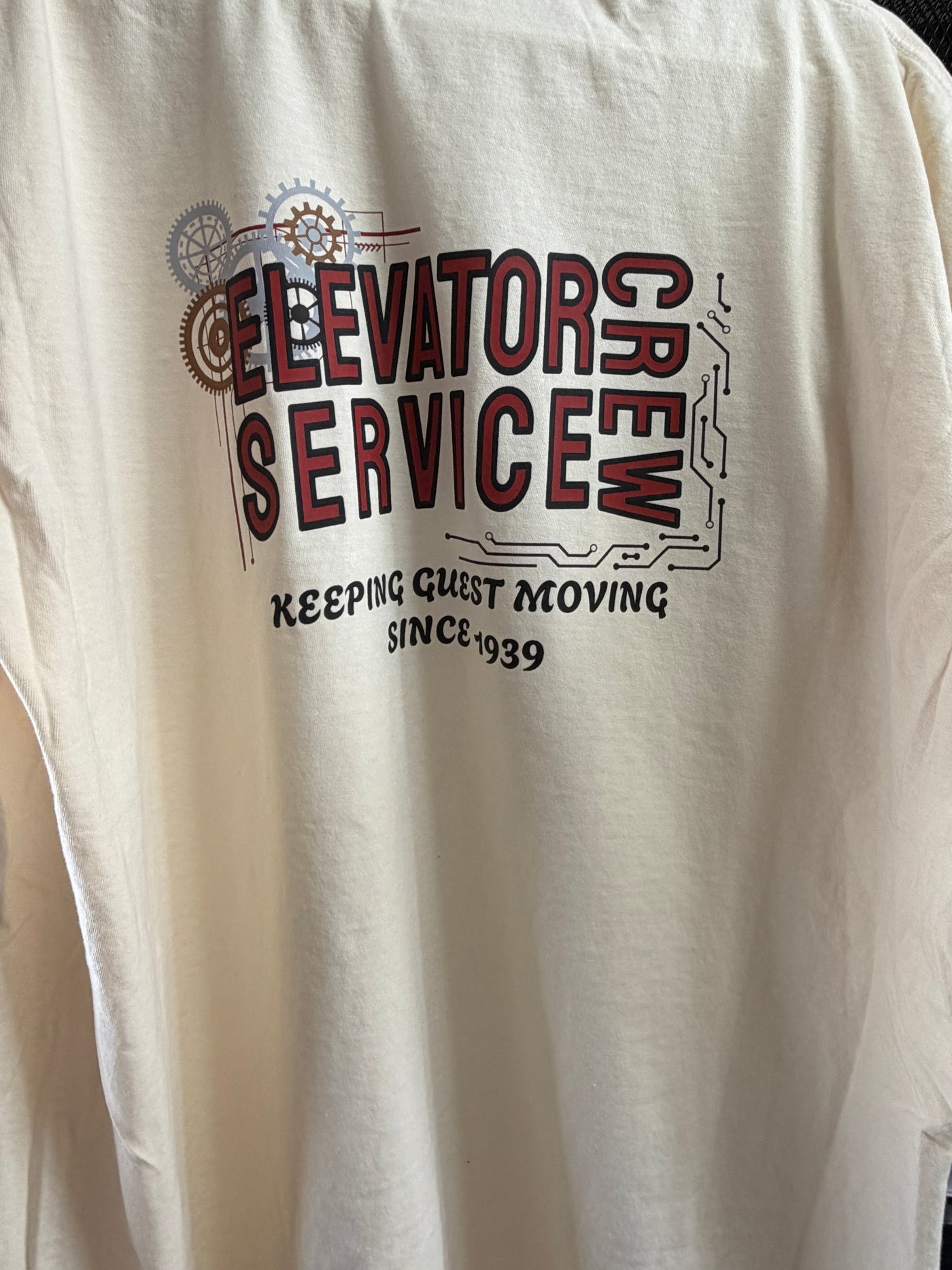 Cream t-shirt with 'Elevator Service Crew' text and gear graphic, Disney-inspired apparel