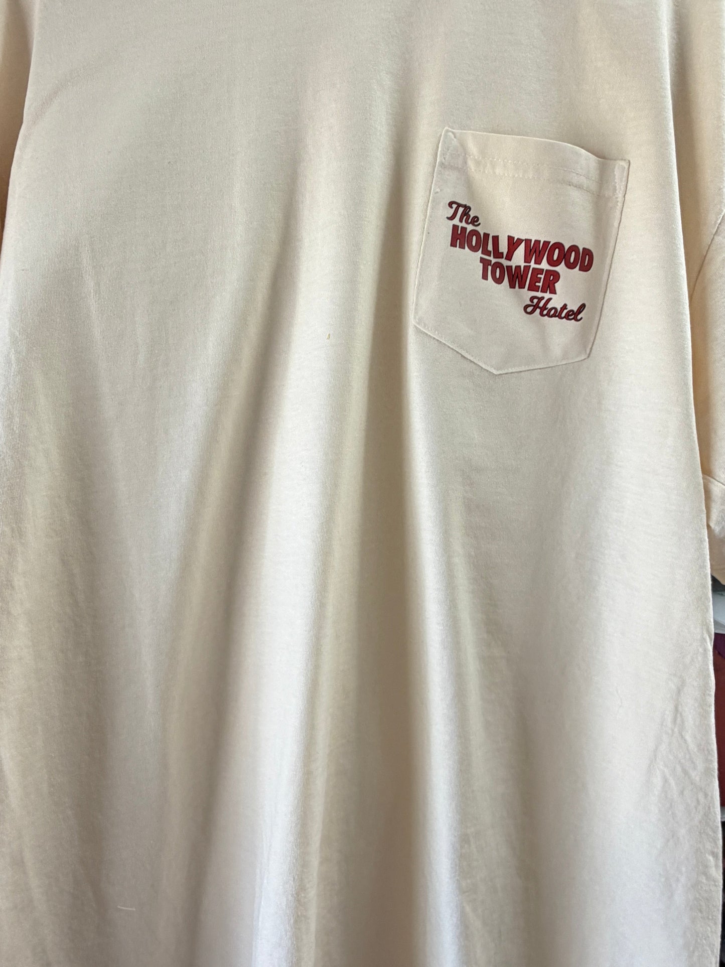 Beige t-shirt with front pocket featuring The Hollywood Tower Hotel text in red.