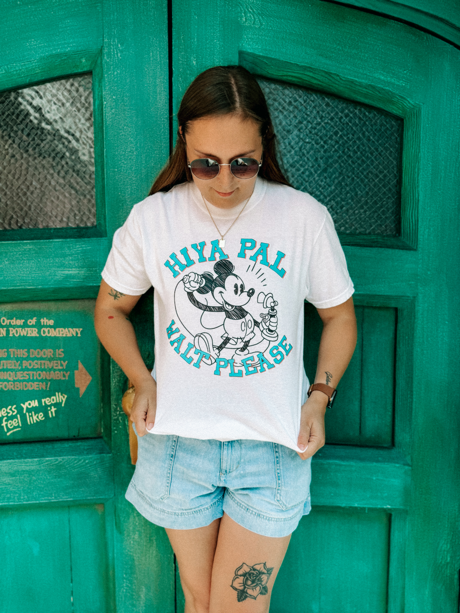 Woman in sunglasses wearing a Disney-inspired 'Hiya Pal' Mickey Mouse t-shirt and denim shorts