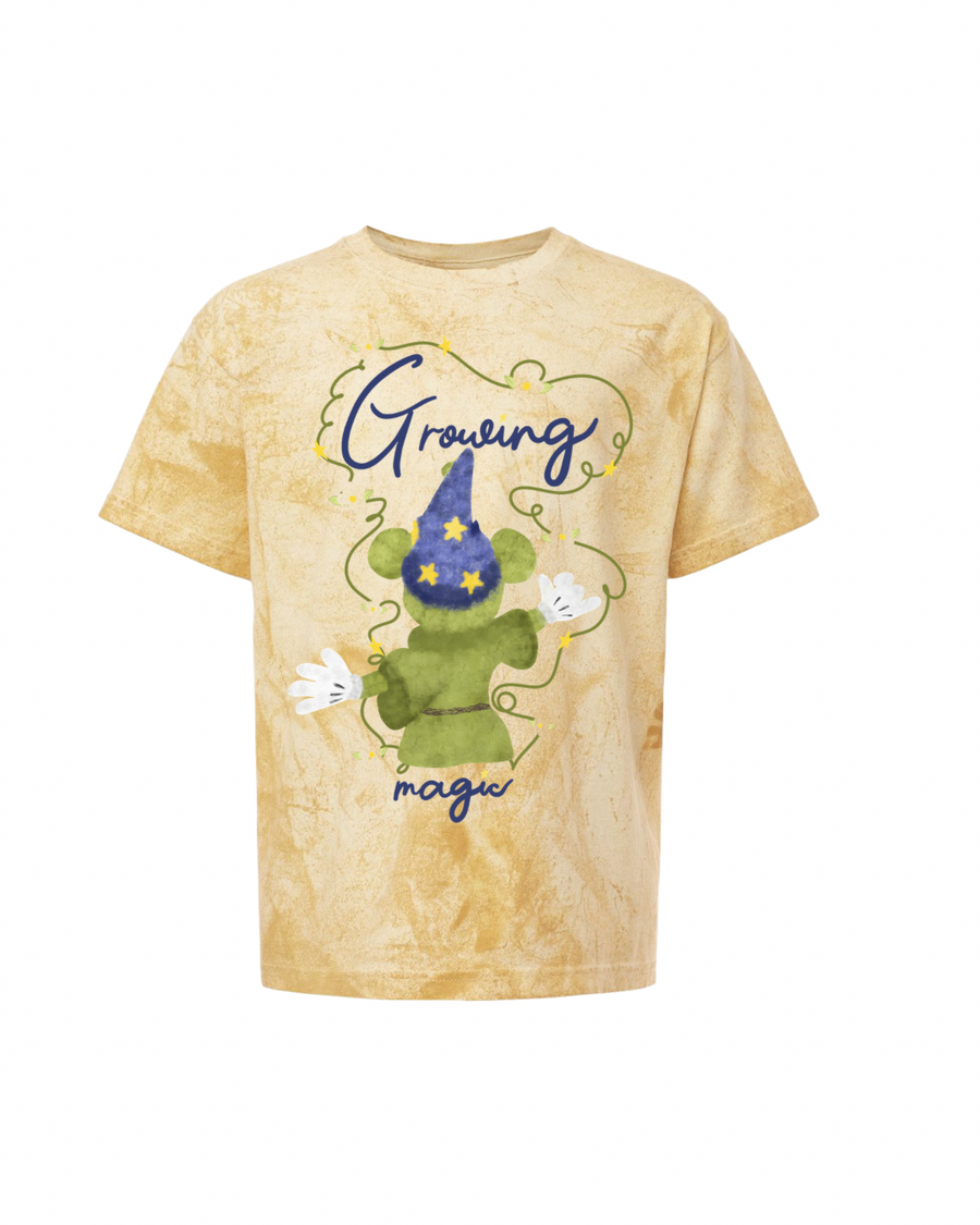 Beige t-shirt with green cartoon mouse wearing wizard hat, stars, gloves, and 'Growing magic' text