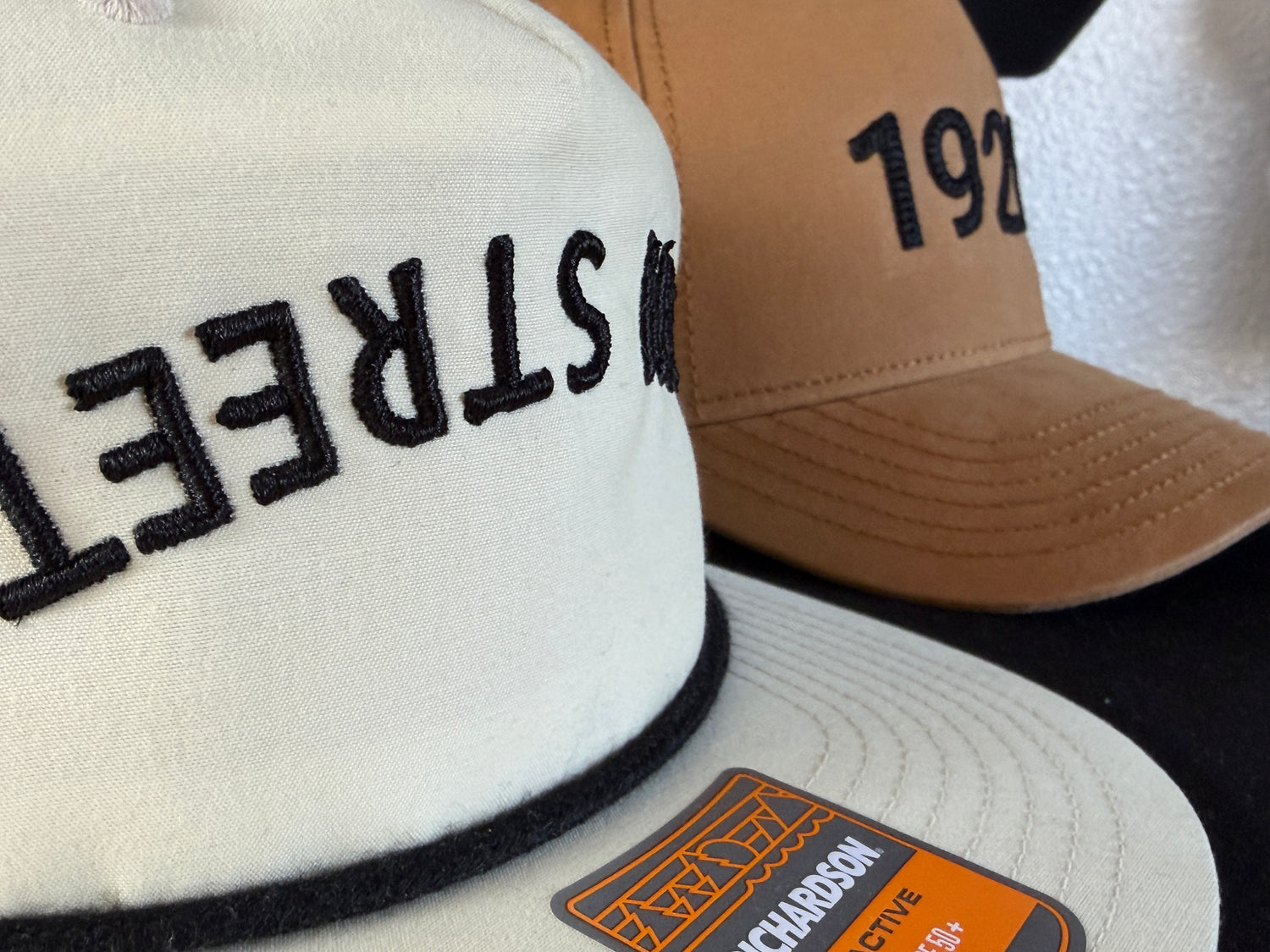 Close-up of embroidered baseball caps, one reading STREET and another with 192, neutral tones