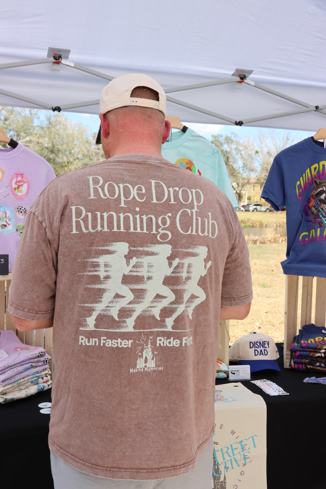 Man wearing Rope Drop Running Club Disney-inspired graphic tee at outdoor apparel booth