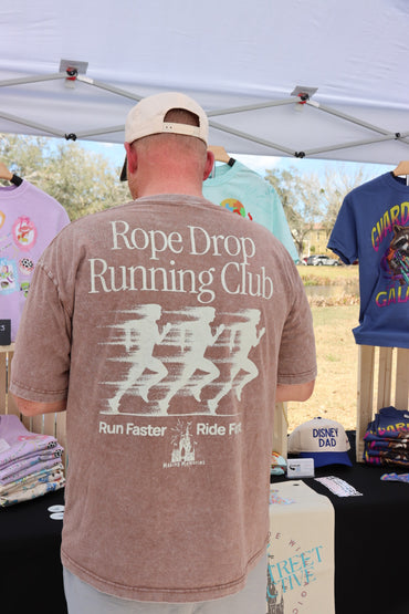 Man wearing Rope Drop Running Club Disney-inspired graphic tee at outdoor apparel booth