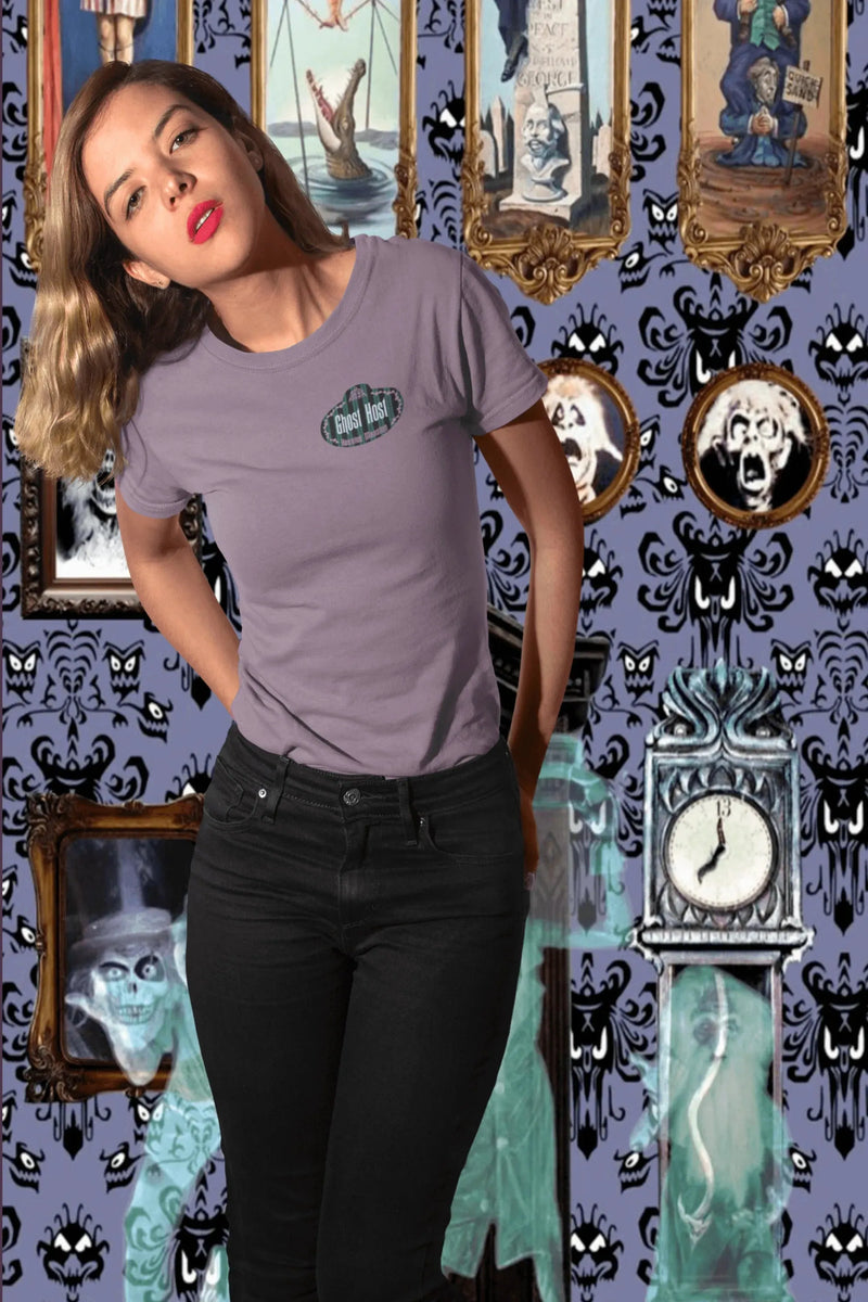 Woman wearing a purple Ghost Host t-shirt with a spooky mansion-inspired background and portraits.
