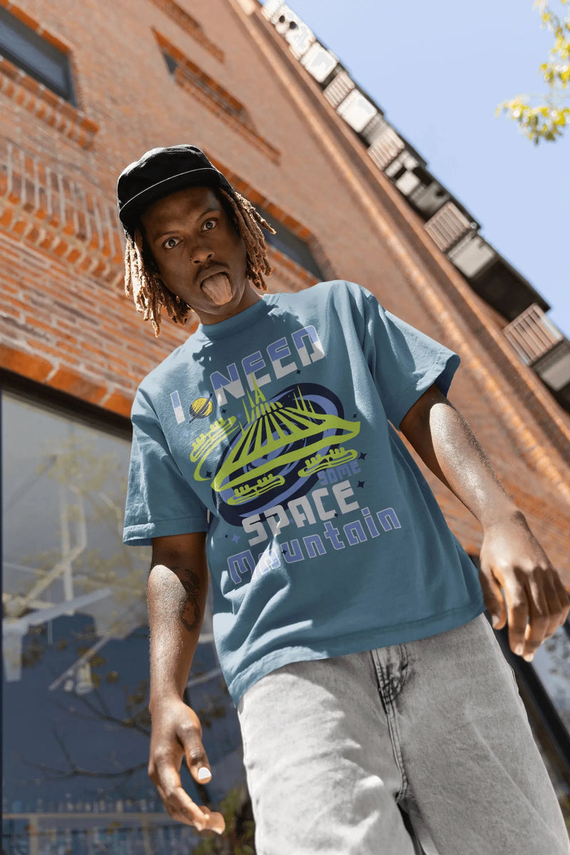 Man in blue Space Mountain graphic shirt and cap posing outdoors in front of brick building