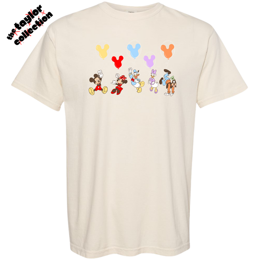 Beige t-shirt with cartoon character designs and balloons on a white background