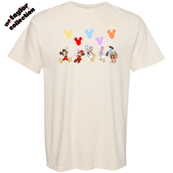 Beige t-shirt with cartoon character designs and balloons on a white background