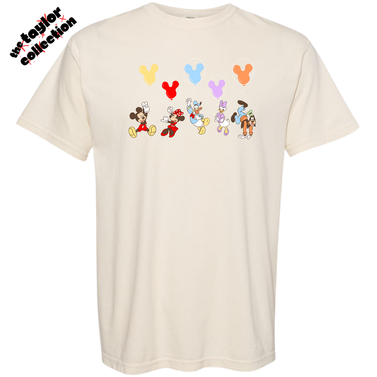 Beige t-shirt with cartoon character designs and balloons on a white background