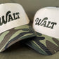 Two hats with 'WALT' branding on a green background